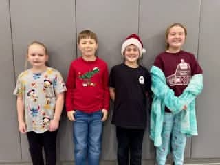 Four Mayflower students posing together in festive clothing
