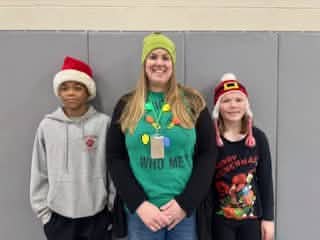 An adult and two Mayflower students posing in holiday clothing